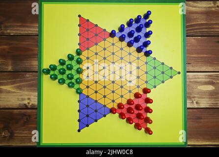 Ansicht von oben nach unten auf isoliertem gelben Gamboard mit Sechseck, bunten Spielsteinen, Holzhintergrund - chinesische Dame (Sternhalma) Stockfoto