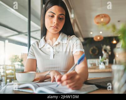 Als Student erfordert Engagement. Eine junge Studentin, die in einem Café arbeitet. Stockfoto