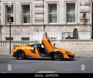 London, Großbritannien - 2022. April: Ein orangefarbener McLaren 600LT parkte vor dem luxuriösen Corinthia Hotel Stockfoto