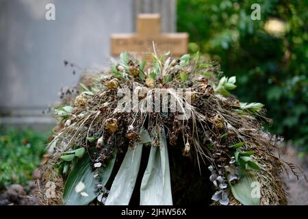 Getrocknete Blumendekoration auf einem traurigen verlassenen Grab Stockfoto