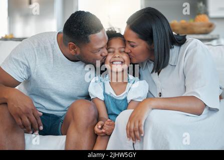 Vergessen Sie nicht zu glänzen. Eine junge Familie, die sich mit ihrer Tochter auf dem Sofa zu Hause verklebt. Stockfoto