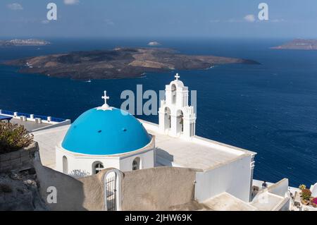 Die katholische Kirche der Dormition - drei Glocken von Fira mit seiner blauen Kuppel mit Blick auf die Ägäis und den Vulkan, Fira, Santorini Insel, Griechenland Stockfoto