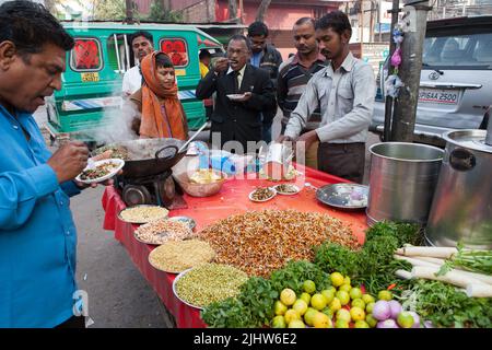 Ein Verkäufer bereitet an seinem Straßenstand in Lucknow einen vegetarischen Snack einschließlich Mungbohnenrouts zu Stockfoto