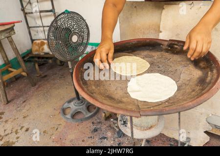 Hände einer lateinischen Frau, die auf einem comal in Bluefields Maistortillas kocht Stockfoto