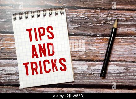 Tipps und Tricks auf Buch mit Holzhintergrund geschrieben. Stockfoto