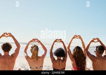 Verbreiten Sie Liebe, wohin Sie gehen. Eine Gruppe von Freunden mit ihren Händen in der Luft schaffen Herzformen. Stockfoto