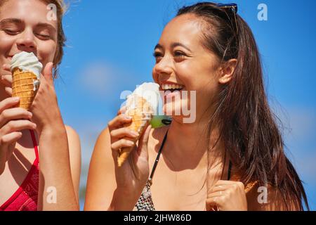 Das sind die Momente, an die man sich gut erinnern kann. Zwei Freunde genießen gemeinsam Eiszapfen. Stockfoto