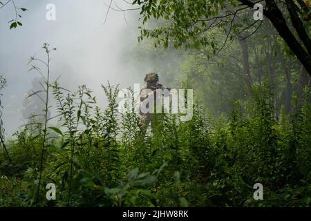 1. Ein Soldat der Charlie Company, 1. Bataillon, 181. Infanterie-Regiment, 44. Infanterie-Brigade-Kampfteam bewegt sich am 19. Juli 2022 während einer Zugangriffsübung während der Übung „Exportable Combat Training Capability“ (XCTC) in Fort Drum, N.Y., durch den Dunst, der durch eine Rauchgranate von M18 verursacht wurde. Mehr als 2.500 Soldaten nehmen an der Trainingsveranstaltung Teil, die es Brigadekampfteams ermöglicht, die geschulte Zugbereitschaft zu erreichen, die für Einsatz, Kampf und Sieg erforderlich ist. Die Soldaten der 181. sind Teil der Massachusetts Army National Guard und der Rest der 44. Infantry Brigade ist CO Stockfoto