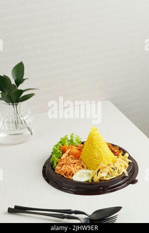 Nasi Tumpeng Mini Agustusan ist kuppelförmiger gelber Reis mit verschiedenen Beilagen, um den indonesischen Unabhängigkeitstag zu feiern Stockfoto
