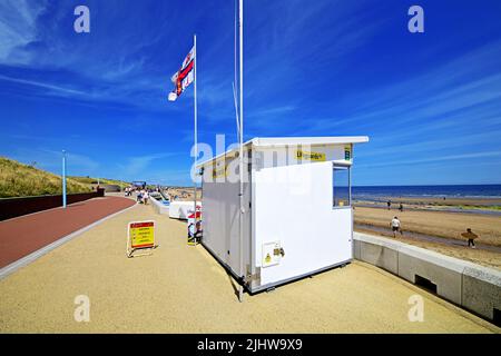 Whitley Bay Promenade an einem sonnigen Tag am Strand mit Spaziergängern und einer RNLI-Rettungswache an der Nordsee und einem tiefblauen Himmel mit Zirruswolken Stockfoto