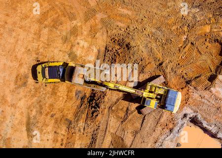 Bagger werden verwendet, um Boden für die Verladung in Muldenkipper auf Baustellen vorzubereiten, indem die Erde mit Baggern ausgehoben wird Stockfoto