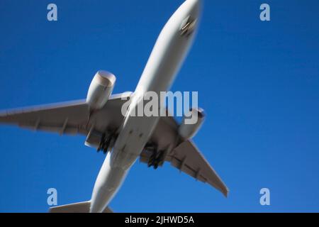 Unterseite eines kommerziellen Jet-Flugzeugs im Flug mit Bewegungseffekt. Stockfoto