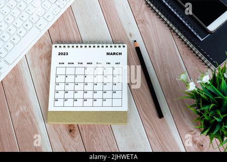 Weißer Tischkalender für März 2023 auf Holzschreibtisch. Direkt darüber. Flach liegend. Stockfoto