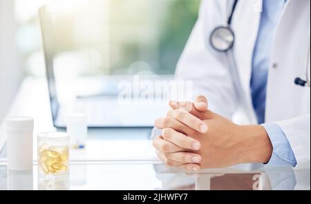 Der Spezialist im Gesundheitswesen. Nahaufnahme einer nicht erkennbaren Ärztin, die mit ihren Händen an einem Tisch in einem medizinischen Büro sitzt. Stockfoto