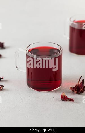 Kräutertee aus Hibiskusblüten in einer transparenten Tasse. Stockfoto