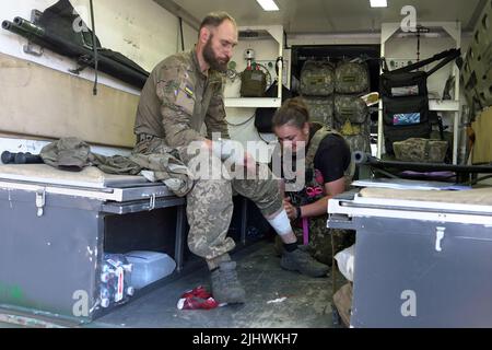 Nicht exklusiv: TschasIV JAR, UKRAINE - 17. JULI 2022 - Ein Sanitäter bandagierte das Bein eines ukrainischen Soldaten, Tschasiv Jar, Bezirk Bakhmut, Donezk Region, Stockfoto