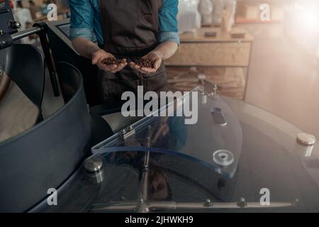 Baristas Hände zeigen frisch geröstete Kaffeebohnen bereit zum Verkauf Stockfoto