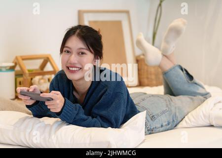 Junge Frau spielt Spiele auf dem Smartphone. Frau mit Video-Streamning. Technologie und Menschen Konzept. Stockfoto