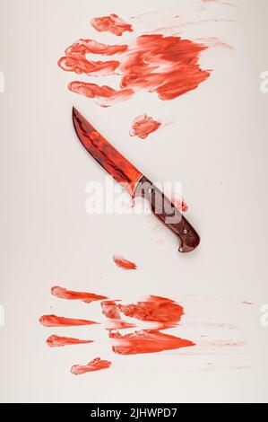 Blutige Messer- und Handdrucke in Blut auf einem weißen Tisch. Stockfoto