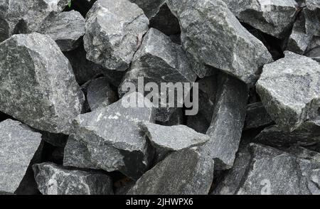 Nahaufnahme eines Stapels großer zerkleinerter Granitsteine, um sie als Baumaterial zu verkaufen Stockfoto