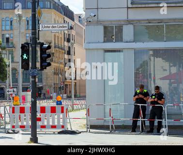 Immer laufende Bauarbeiten sind ein Merkmal Berlins. Unter den Linden mit zwei Polizisten, die auf ihr Handy schauen Stockfoto