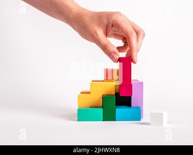 Frau löst logische Rätsel. Konstruktion, Montagekonzept. Entwicklung des analytischen Denkens. Holzspiel für Kinder und Erwachsene aus verschiedenen geometrischen Formen. Hochwertige Fotos Stockfoto