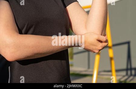 Sportlerin mit Ellenbogenschmerzen. Entzündung und Schwellung der Armsehnen. Gesundheitliche Probleme durch Sport-Konzept verursacht. Hochwertige Fotos Stockfoto