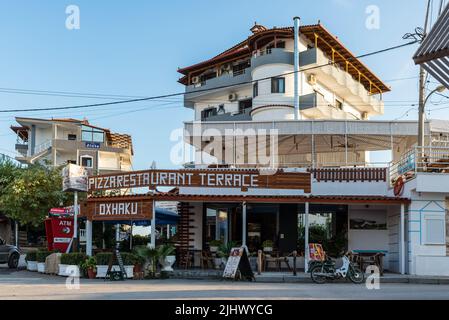 Ksamil, Albanien - 9. September 2021: Straßenansicht von Ksamil am Tag mit dem Restaurant Pizza Oxhaku in der Nähe der Hotels in Ksamil, Albanien. Stockfoto