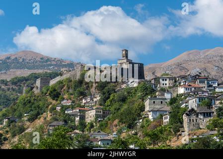 Gjirokaster, Albanien - 10. September 2022: Landschaft mit einem Gjirokaster Schloss und Uhrturm mit osmanischen Häusern unten in Gjirokaster, Albanien. Stockfoto