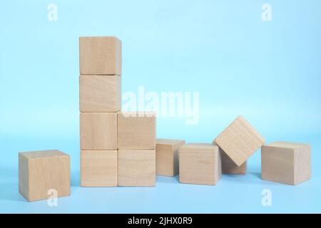 Eingestürzte Holzbausteine auf blauem Hintergrund. Schwache Grundlage und gebaut konzeptuell. Stockfoto