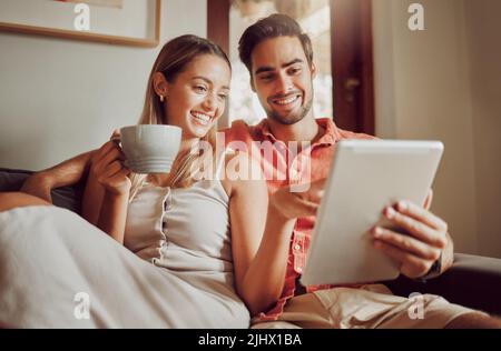 Schauen wir uns das an. Ein junges Paar, das zu Hause ein digitales Tablet nutzt. Stockfoto