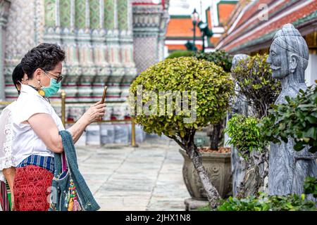 Bangkok, Thailand. 20.. Juli 2022. Ein Tourist fotografiert Steinstatuen im Wat Phra Kaew Tempel des Großen Palastes in Bangkok, Thailand, 20. Juli 2022. Im Juli 2021 wurden vor dem Großen Palast eine Reihe von Steinstatuen freigelegt, von denen einige mit chinesischen Schriftzeichen graviert waren. Vor kurzem wurden die restaurierten Statuen im Wat Phra Kaew Tempel des Großen Palastes ausgestellt. Quelle: Wang Teng/Xinhua/Alamy Live News Stockfoto
