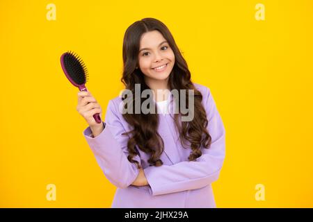 Teenager putzen Kämmen Haare mit großen Kamm auf gelb isoliert Studio Hintergrund. Teen Mädchen mit Haarbürste. Kinderfrisur. Glücklich positiv und Stockfoto