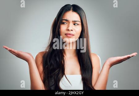 Warum mag ich lange Haare, weil ich sie schalten kann. Studioaufnahme einer schönen jungen Frau mit halb gelockenem Haar und halb gerade. Stockfoto