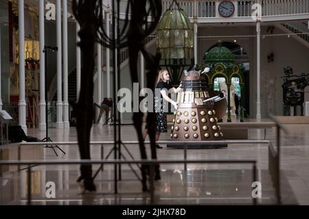 Edinburgh. Schottland, Großbritannien. 21.. Juli 2022. Das National Museum of Scotland kündigt die große Ausstellung „Doctor Who“ an. Diese bahnbrechende neue Ausstellung, die vom 10. Dezember 2022 bis zum 30. April 2023 stattfindet, wird die Wissenschaft hinter der weltweit erfolgreichen Fernsehserie Doctor Who erforschen und den Fans die Möglichkeit geben, die Abenteuer des Doktors aus wissenschaftlicher Perspektive zu erleben. Im Bild: Liv Mullen schiebt den Dalek aus der erfolgreichen Fernsehserie, die durch die legendäre Grand Gallery des National Museum of Scotland gerollt wird. Pic Credit: Pako Mera/Alamy Live News Stockfoto