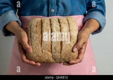 Junge Frau hält frisch hausgemachtes rustikales Brot - Stock Foto Stockfoto