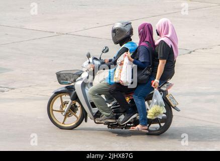 Ein Taxifahrer auf einem Motorrad fährt mit einer zwei Frau im Hijab. Stockfoto