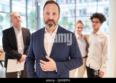 Kompetenter Geschäftsmann als Manager und Chef vor seinem Team im Büro Stockfoto