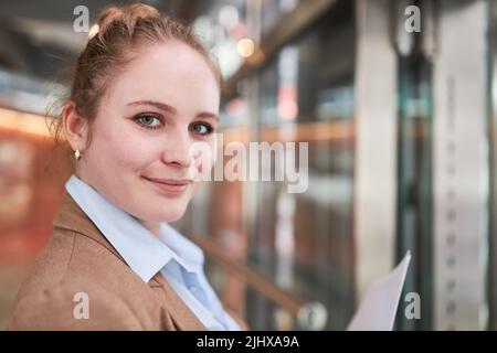 Lächelnde junge Frau als Auszubildende oder Studentin Stockfoto