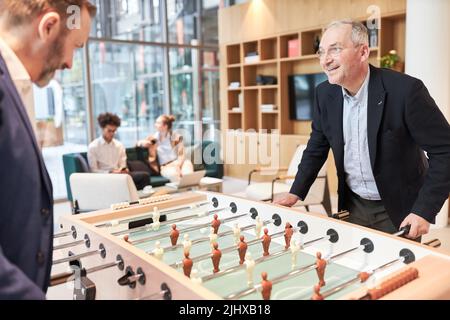 Zwei Geschäftsleute am Tischfußball spielen im Büro Tischfußball, um sich zu entspannen Stockfoto