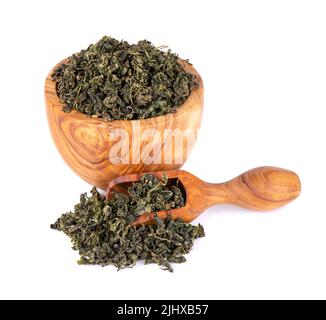 Trockenes gynostemma pentaphyllum Blatt in Olivenschale und Löffel, isoliert auf weißem schwarzen Grund. Jiaogulan oder Wundergras. Chinesischer Kräutertee Stockfoto