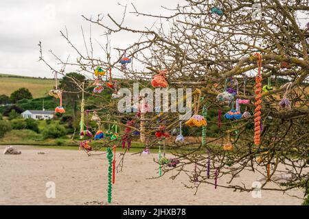 Nahaufnahme der dekorativen Strandkunst, die von Handwerkern in Handarbeit hergestellt und in natürlichen Bäumen am Strand aufgehängt wurde Stockfoto