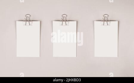 Leere weiße Papiere mit einer Büroklammer auf grauem Hintergrund, Platz für Text, Erinnerung oder Nachricht im Büro, Kommunikationskonzept Stockfoto