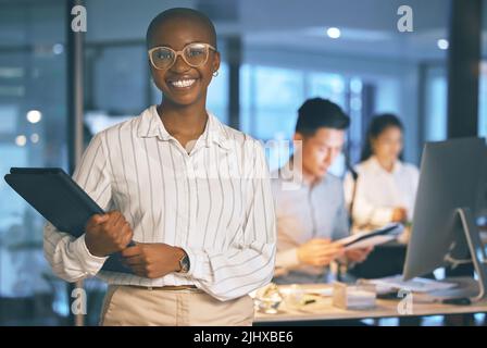 Eine junge Geschäftsfrau, die spät in der Nacht in einem modernen Büro stand. Stockfoto
