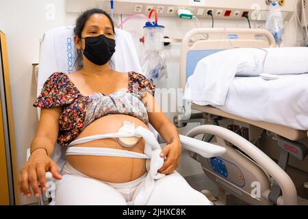 Herz-Kreislauf-Überwachung der Schwangeren Latino-Mutter im Krankenhaus vor der Geburt, um Komplikationen zu vermeiden Stockfoto