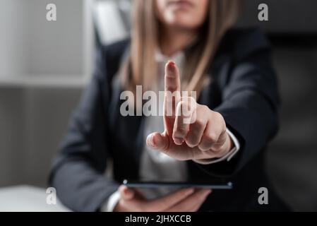 Geschäftsfrau Hält Tablet In Einer Hand Und Zeigt Mit Einem Finger Auf Wichtige Botschaft. Sitzende Frau Im Büro Mit Mobiltelefon In Der Hand Präsentieren Stockfoto