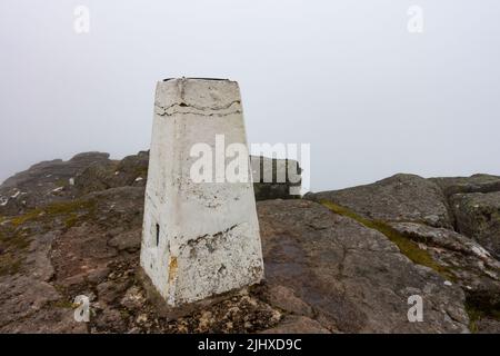 Der weiße trig Point auf dem Gipfel des corbett Bergs von Ben Rinnes in der Nähe von Dufftown, Morayshire, Schottland an einem nebligen Tag Stockfoto