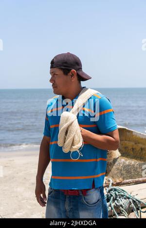 Arbeiter schaut weg, während er ein Fischernetz trägt Stockfoto