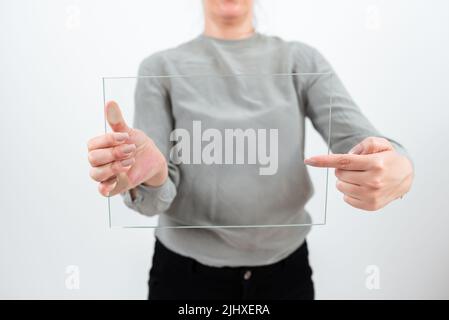 Weibliche Professionelle Holding Und Zeigt Auf Transparentes Glas Während Der Anzeige Von Daten. Frau Trägt Smart Casual Zeigt Banner Und Die Förderung Der Stockfoto