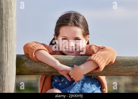 Mir gefällt es hier sehr gut. ein entzückendes kleines Mädchen, das draußen auf der Farm spielt. Stockfoto